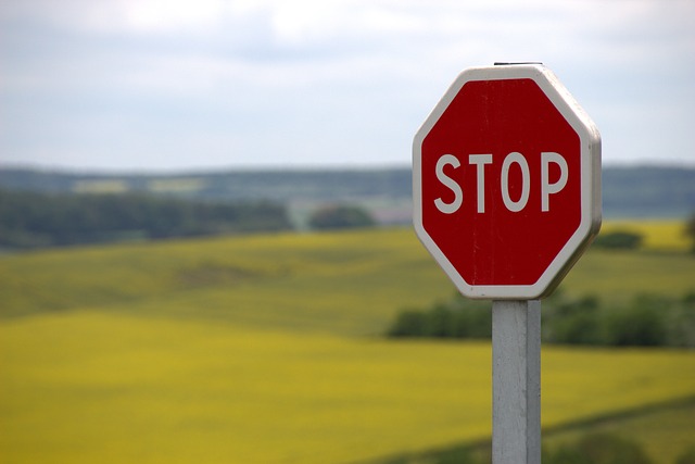 A stop sign is in the foreground with rolling green hills in the background.